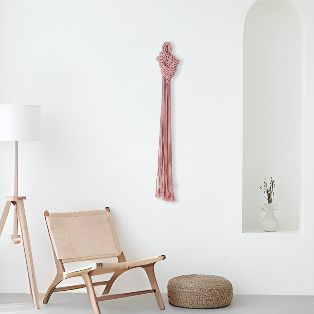Pink hand-knotted rope sculpture with intricate details, adding artistic flair to a bright modern space.