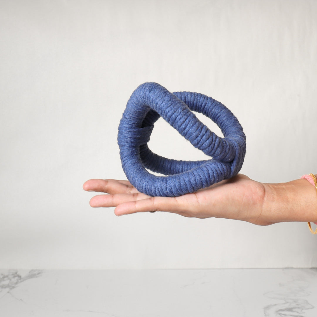 A bold, three-dimensional abstract rope sculpture in blue color, is handmade with one continuous piece of rope for table and shelf decor. Perfect for beach and coastal living rooms.