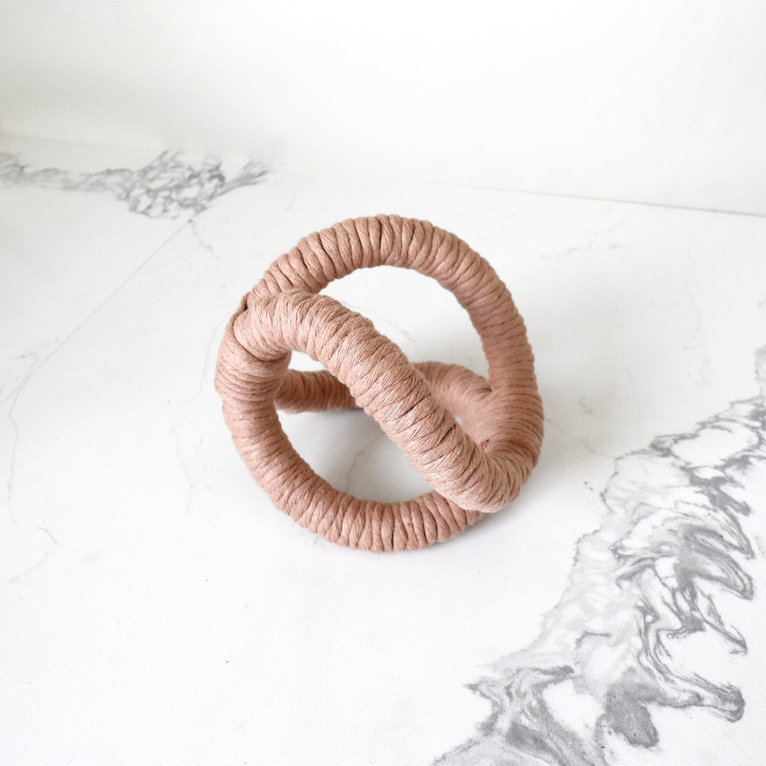 Infinity loop Knot sculpture in Peach Fuzz color. A bold, three-dimensional abstract rope sculpture, is handmade with one continuous piece of rope for table and shelf decor.