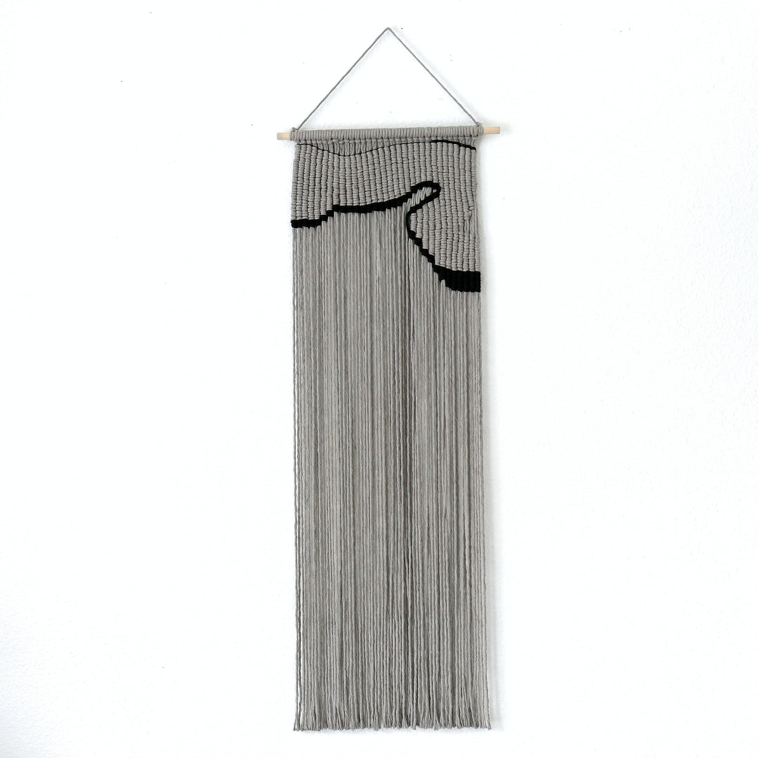 Contemporary gray macrame wall hanging with a nunique and modern black design, creating a modern and artistic statement in any space or interior 
