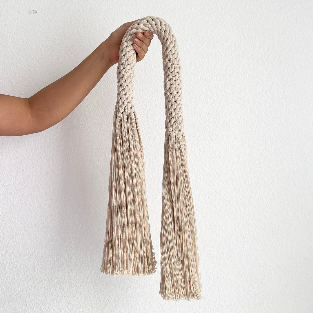 Fiber art wall hanging featuring a knotted tassel design- Aarya in a oat color,made from cotton rope showcasing intricate design and knotwork handcrafted by Yashi Designs.