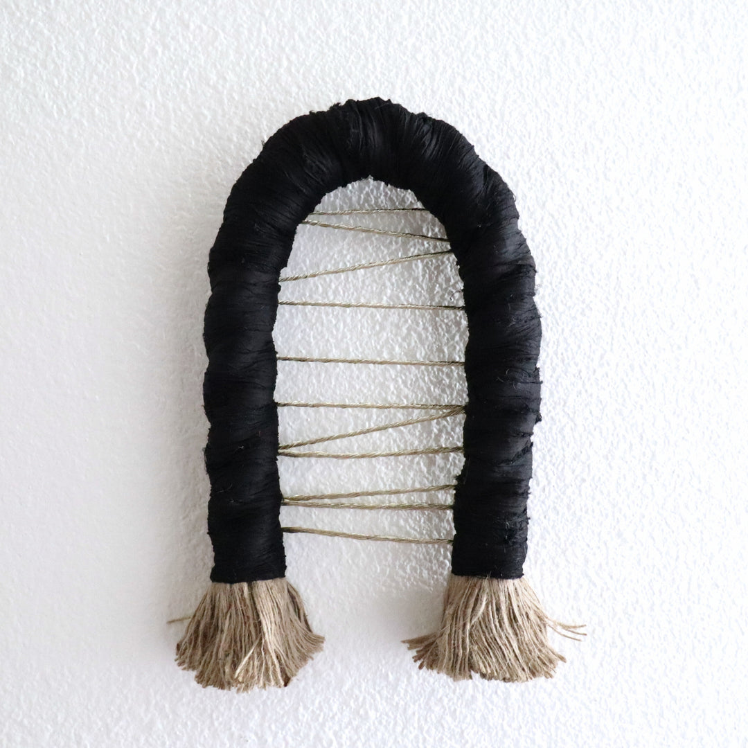 Handcrafted black color knotted rope sculpture Arch by Yashi Designs made from natural Jute, gold thread and saree silk ribbon, showcasing intricate knotwork and modern design.