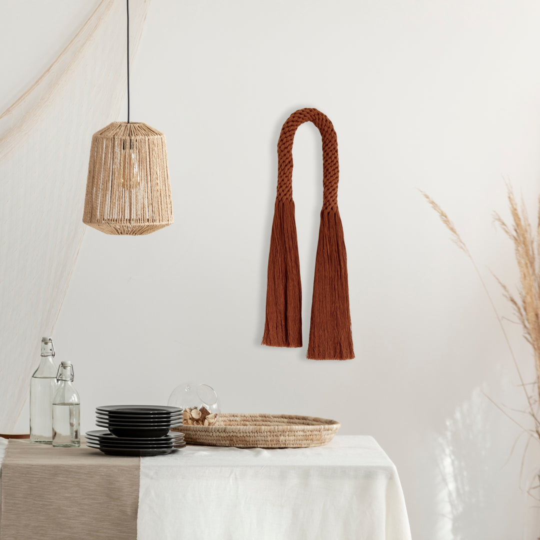 Fiber art wall hanging featuring a knotted tassel design- Aarya in a Rust color,made from cotton rope showcasing intricate design in modern organic interiors handcrafted by Yashi Designs.