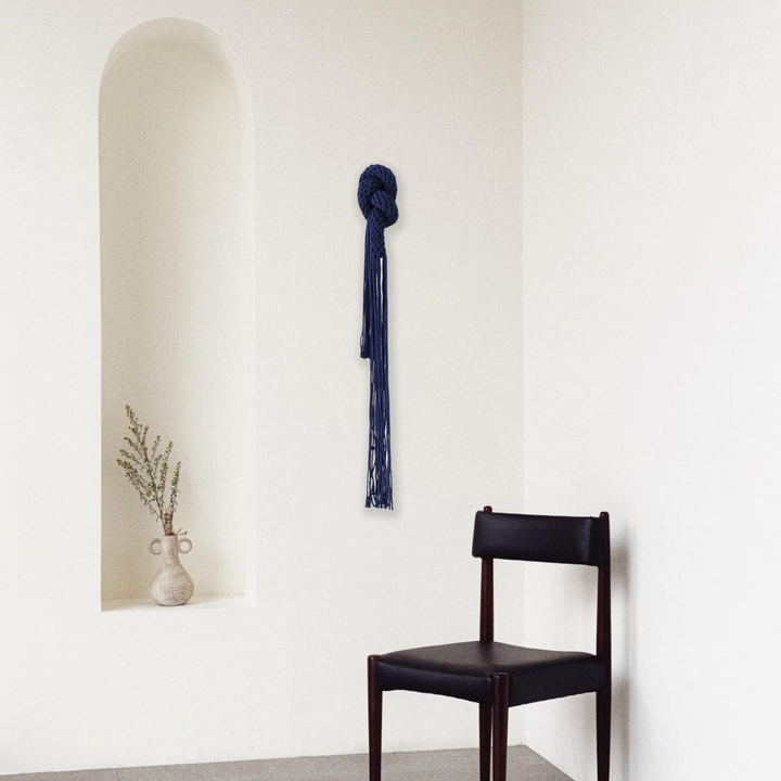 Hand-knotted fiber art showcased in a minimalistic space, adding artistic elegance to the room's decor.