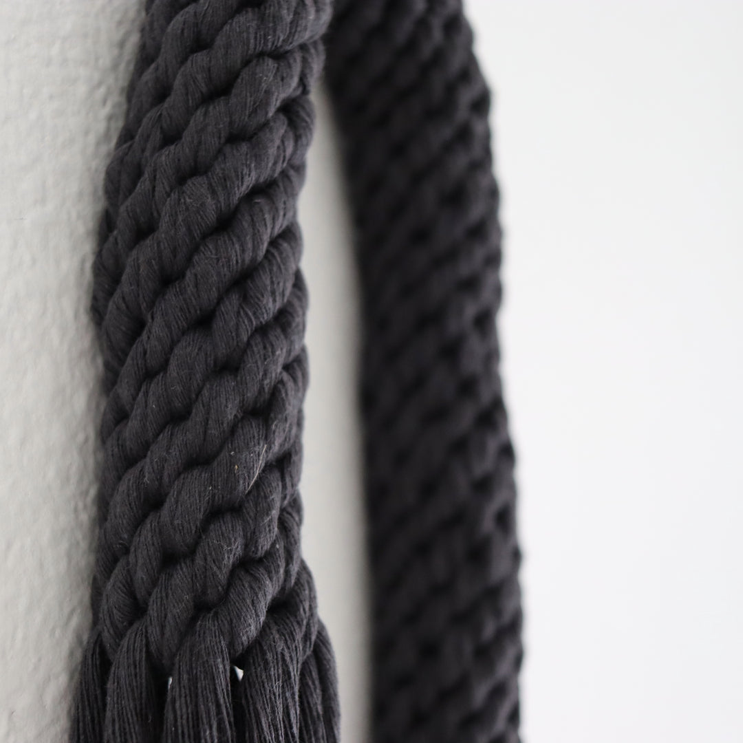 Elegant fiber art wall hanging featuring a knotted tassel design in a soothing black color, handcrafted by Yashi Designs knotted Rope Sculpture - Aarya in Black Color
