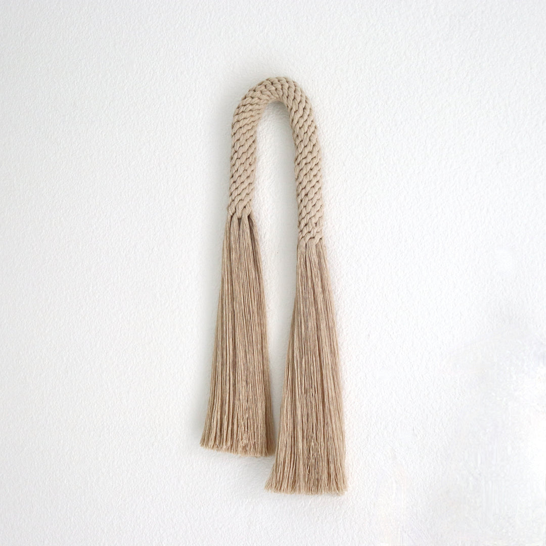 Fiber art wall hanging featuring a knotted tassel design- Aarya in a oat color,made from cotton rope showcasing intricate design and knotwork handcrafted by Yashi Designs.