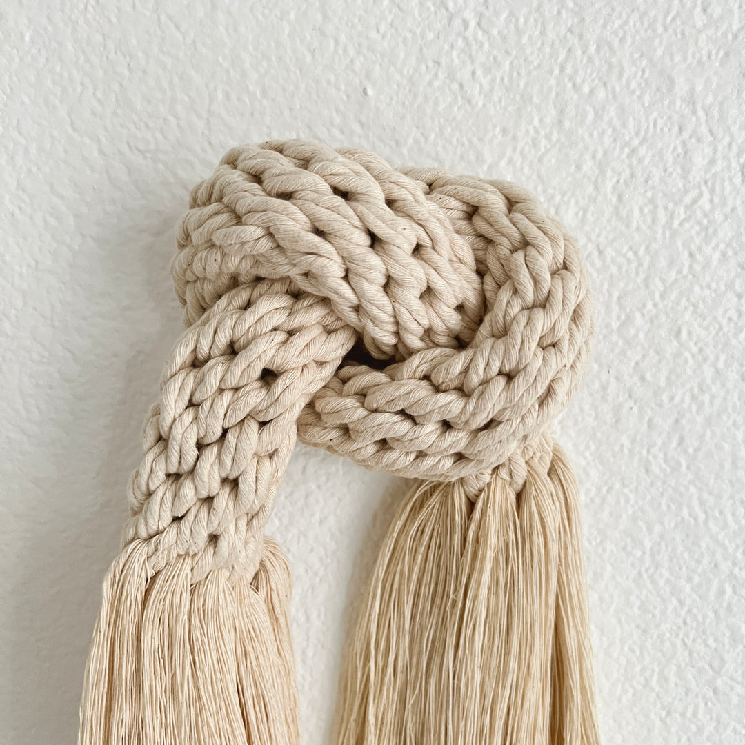 Handmade macrame-inspired knot wall hanging with soft fringe.