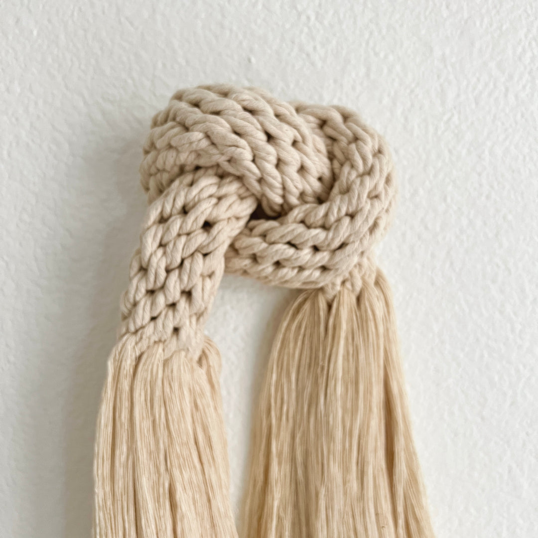 Detail of Handmade macrame-inspired knot wall hanging with soft fringe.